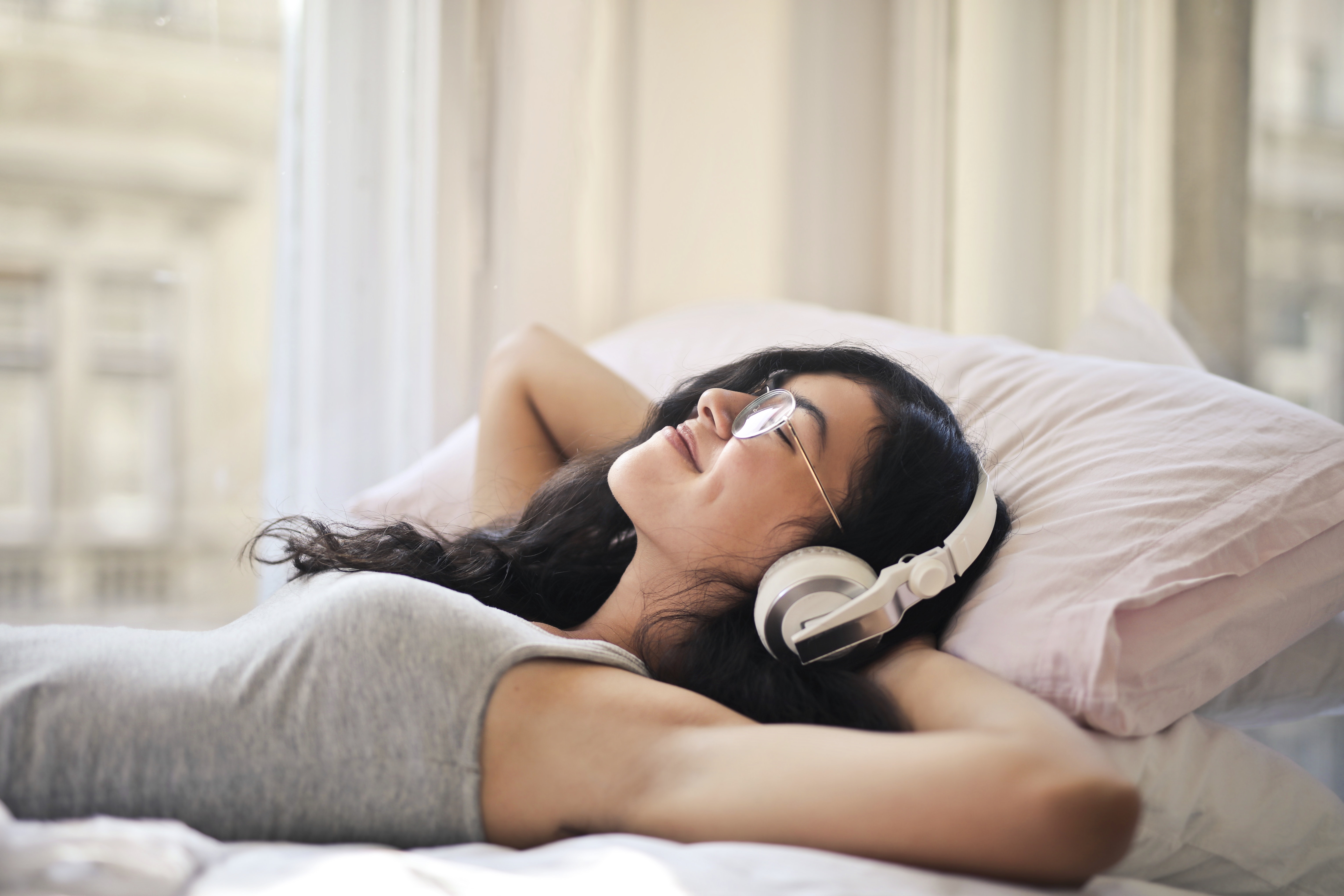woman-in-gray-tank-top-lying-on-bed-with-headphones-on.jpg