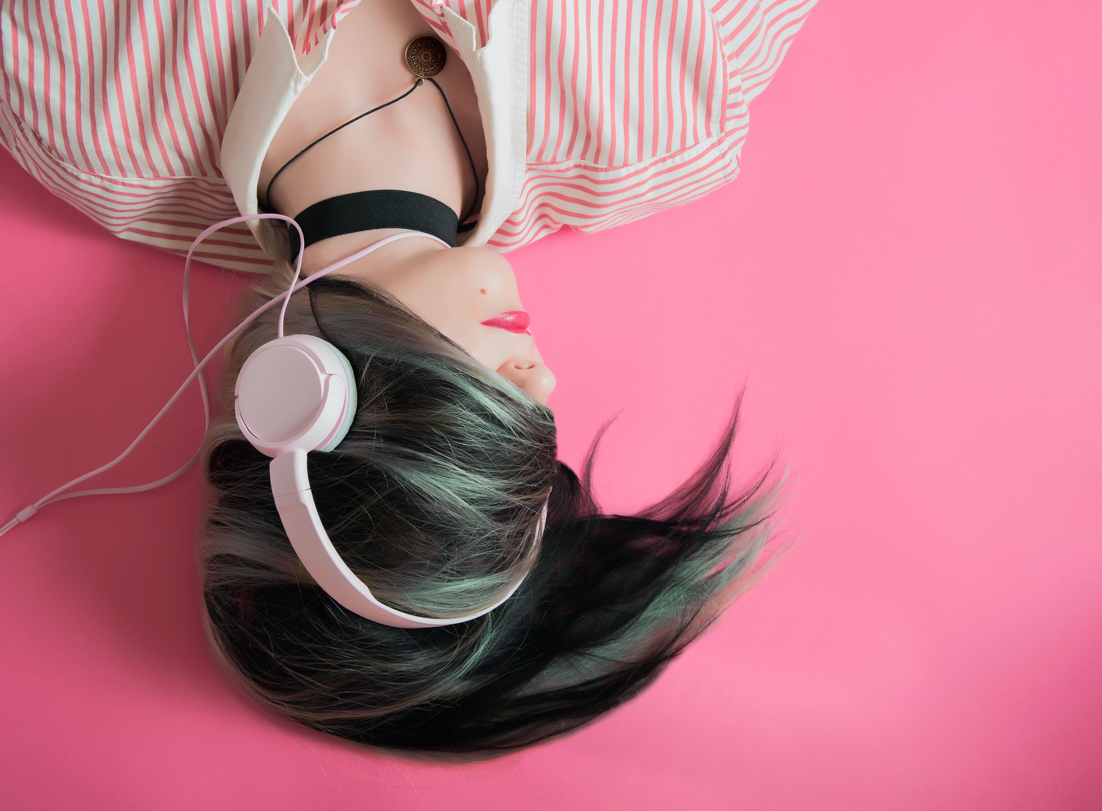 woman-lying-with-headphones-on-pink-background.jpg