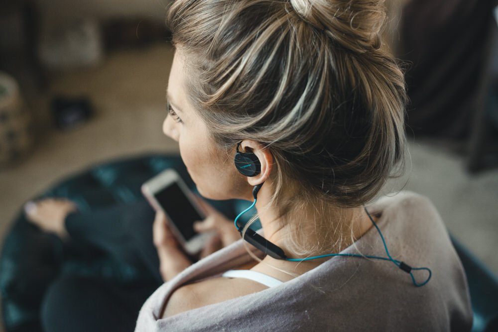 Woman holding phone while listening to Bedphones Wireless Sleep Headphones